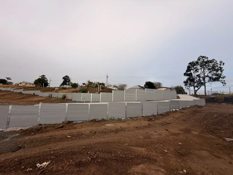 Wide view of tiered sleeper retaining walls across a civil development site