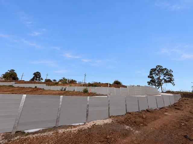 Long grey sleeper retaining wall following a civil site boundary