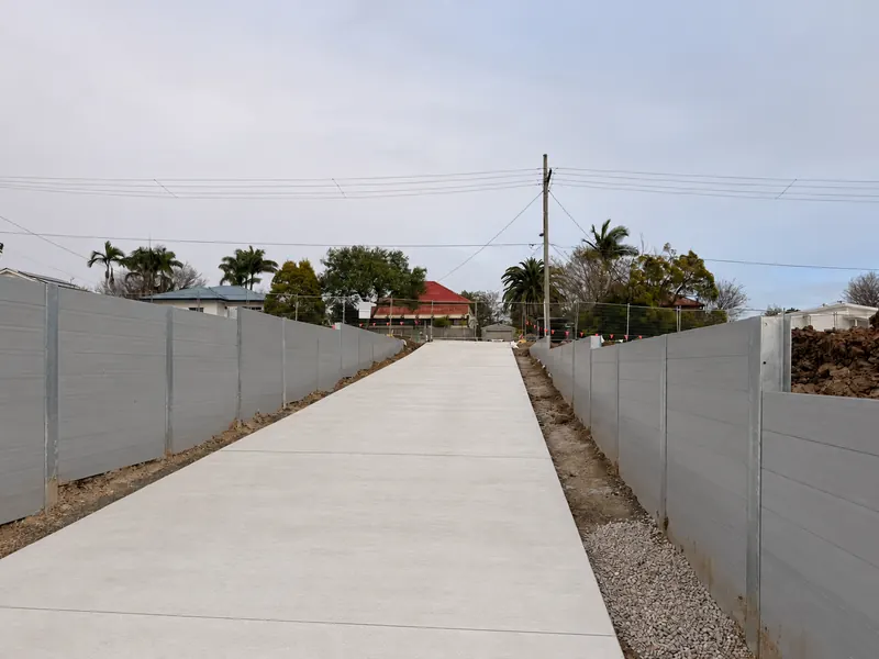 Grey sleeper retaining walls lining a concrete access driveway