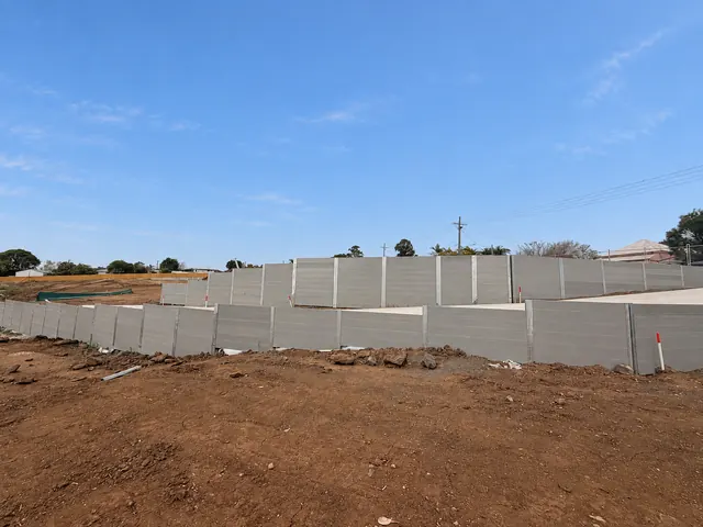 Wide view of tiered grey sleeper retaining walls across a civil construction site
