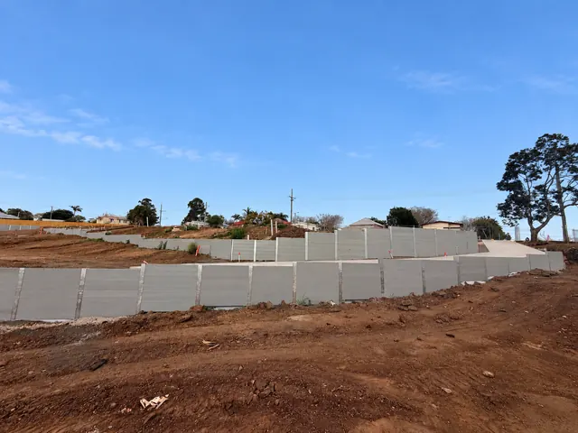 Stepped sleeper retaining walls and steel posts across a large earthworks site