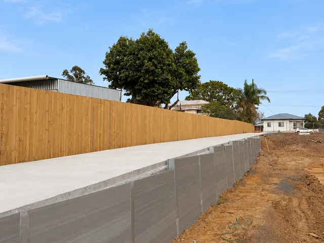 Side view of a sleeper retaining wall and timber fencing beside a new access path