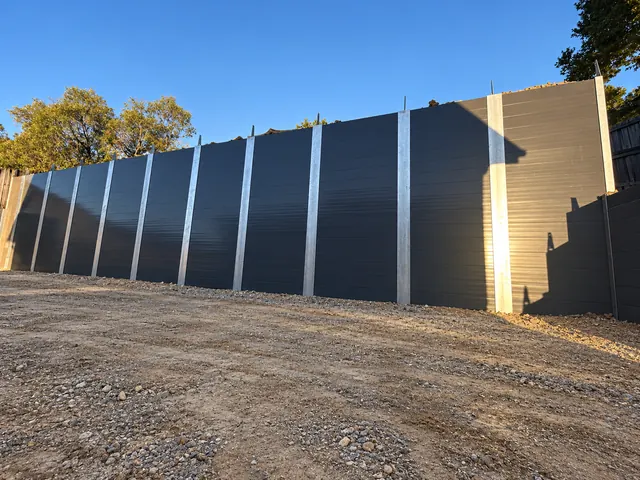 Charcoal sleeper retaining wall with galvanised steel posts on a civil construction site