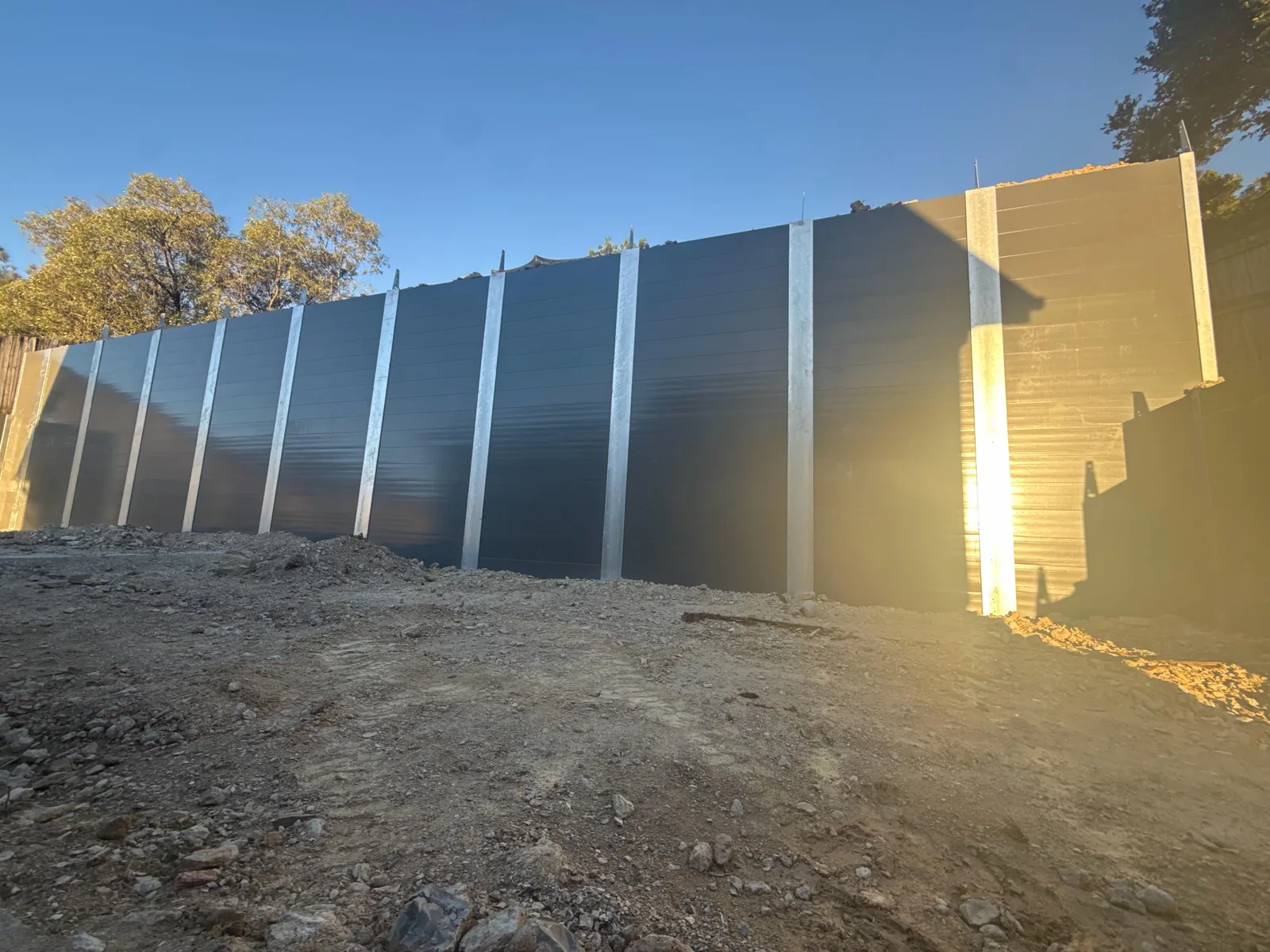 Tall charcoal concrete sleeper retaining wall under construction