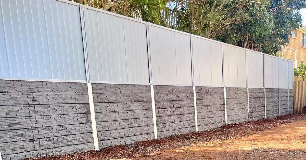Light Colorbond fencing above a stone-finish concrete sleeper wall