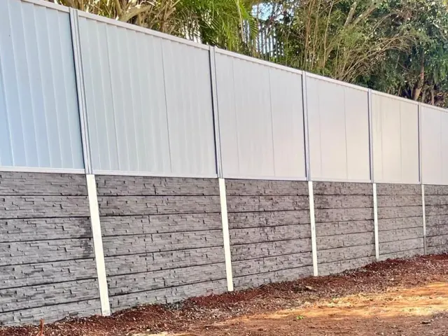 White Colorbond fence above a stone-finish sleeper wall in a backyard