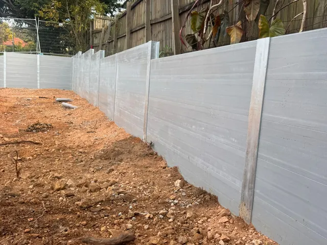 Light sleeper retaining wall below an existing timber fence in a backyard