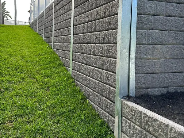 Textured sleeper retaining wall beside a lawn