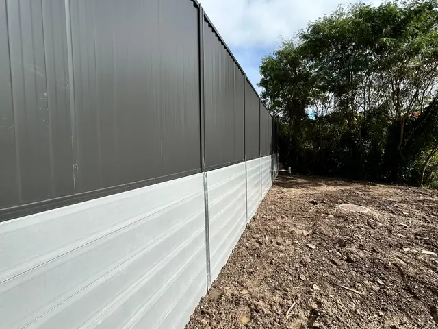 Colorbond fencing and a light sleeper wall extending towards a garden corner