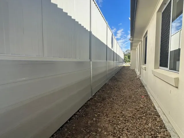 Light sleeper retaining wall and Colorbond fencing beside a house