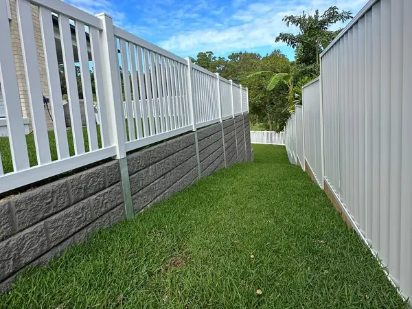 Sleeper retaining wall with white balustrade and boundary fencing