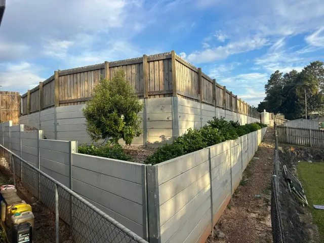 Tiered sleeper retaining walls with planted garden beds and timber fencing