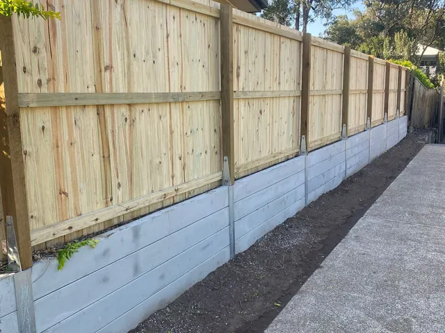 Timber fence and light sleeper wall alongside a concrete path beside a home